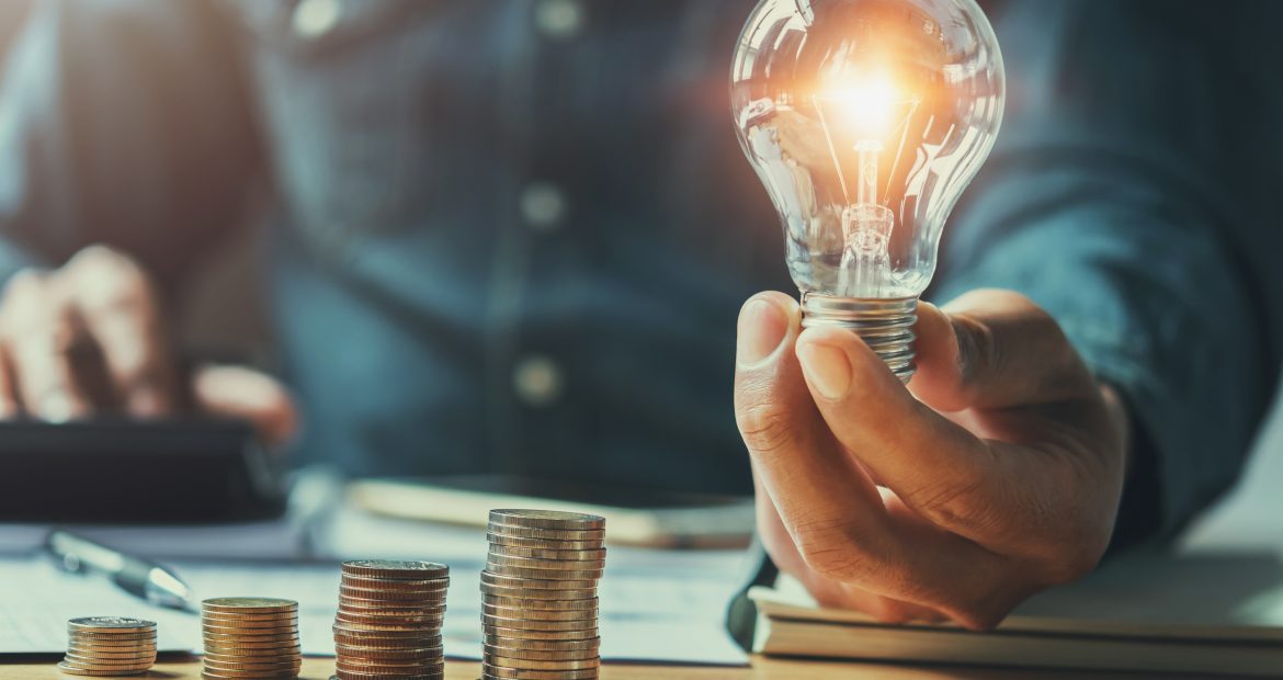 business man hand holding lightbulb with using calculator to cal